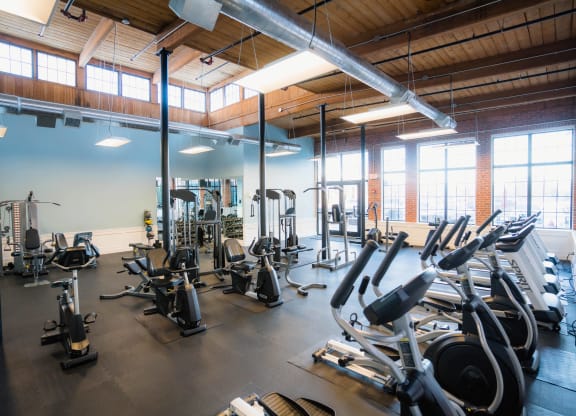a gym with a lot of exercise equipment and windows at Ponemah Mills in Taftville, CT, 06380
