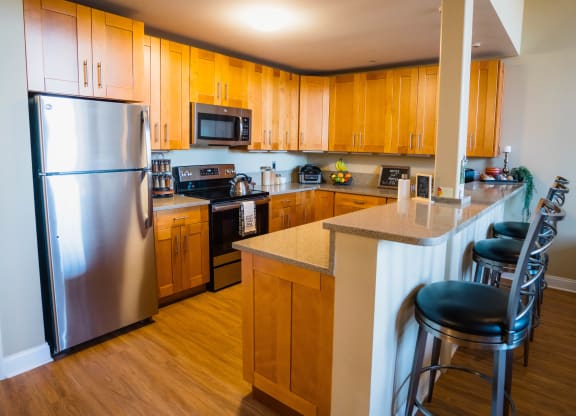a kitchen with wooden cabinets and stainless steel appliances at Ponemah Mills in Taftville, CT, 06380