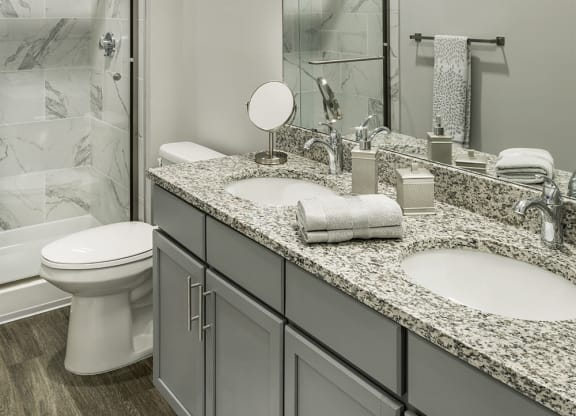 a bathroom with two sinks and a shower and a toilet at The Beacon at Gateway Apartments, Scarborough, ME, 04074