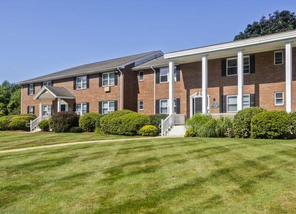 a large brick apartment building with a green lawn at Hawkins Meadow in Amherst, MA, 01002
