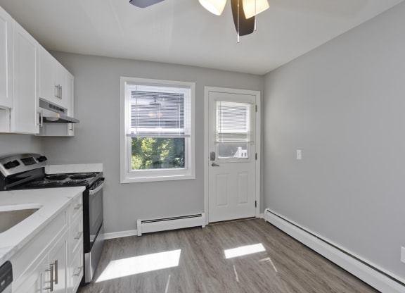 an empty kitchen with white cabinets and a white door and window at Laurel Ridge in Northampton, MA, 01060