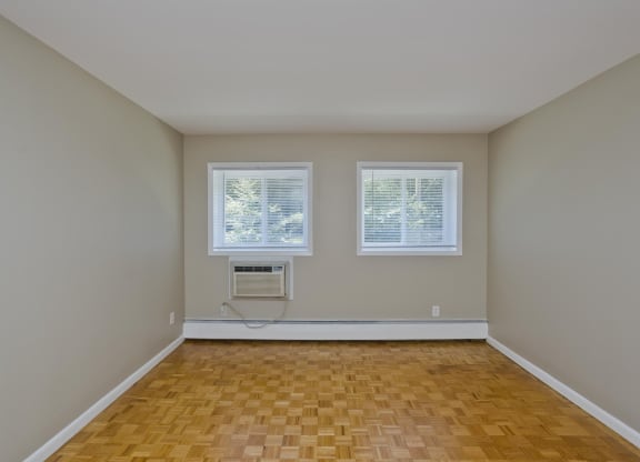 an empty living room with two windows and a wood floor at Park Edge, Springfield, MA