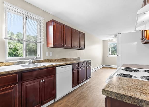 a kitchen with brown cabinets and white appliances and a counter top at Rose Hill Estates, Norwich, Connecticut