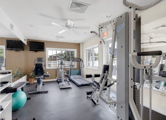 a gym with weights and cardio equipment and a window at St Charles Square Apartments, Carol Stream