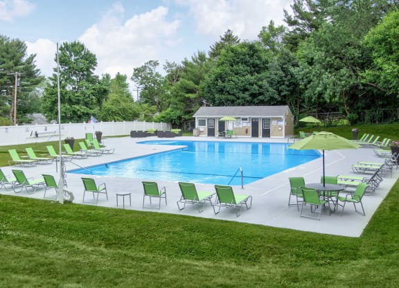 a swimming pool with green chairs and umbrellas in front of a house at Stepny Place, Rocky Hill, Connecticut