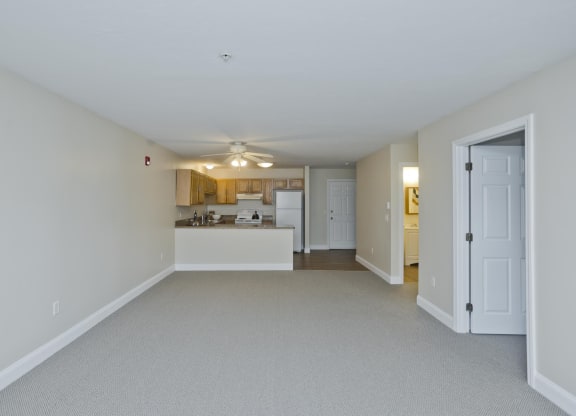 the living room and kitchen of an empty house with a ceiling fan