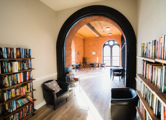 a library with an arched doorway and bookshelves and a table and chairs at Ponemah Mills in Taftville, CT, 06380