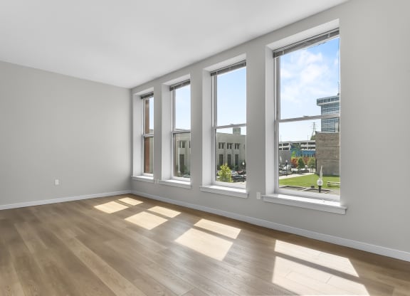 an empty living room with windows and wood floors at 1188 Lofts, Bridgeport