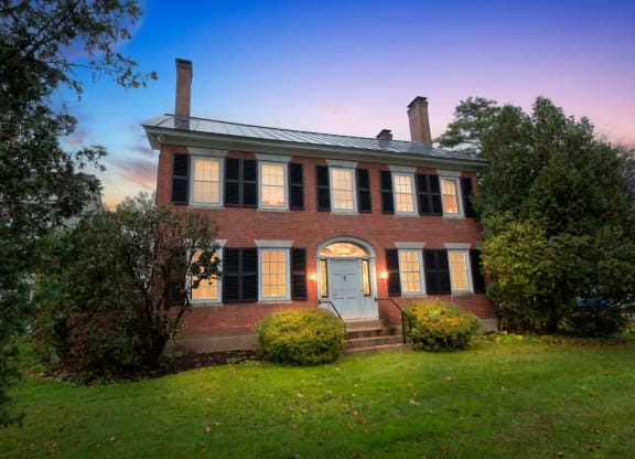 a red brick house with a white door and a green lawn