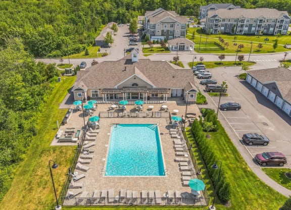 a aerial view of a swimming pool and a house with umbrellas at The Beacon at Gateway Apartments, Scarborough, ME, 04074