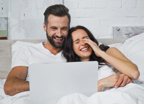Couple watching movie on laptop and laughing