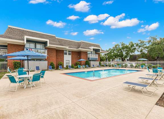 A pool area with chairs and a building in the background.