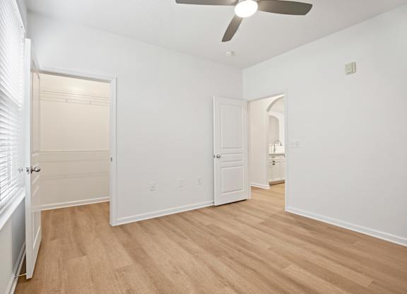 A room with a ceiling fan and wooden flooring.