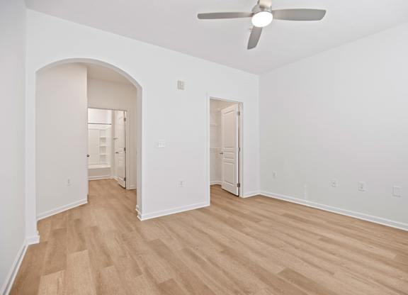 A room with a ceiling fan and wooden flooring.