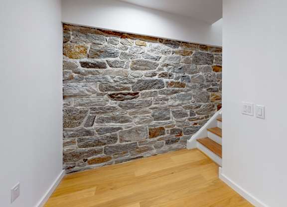 A stone wall with a wooden floor and white walls.