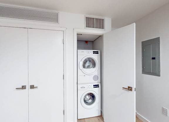 A white door opens to a small laundry room with a washer and dryer.