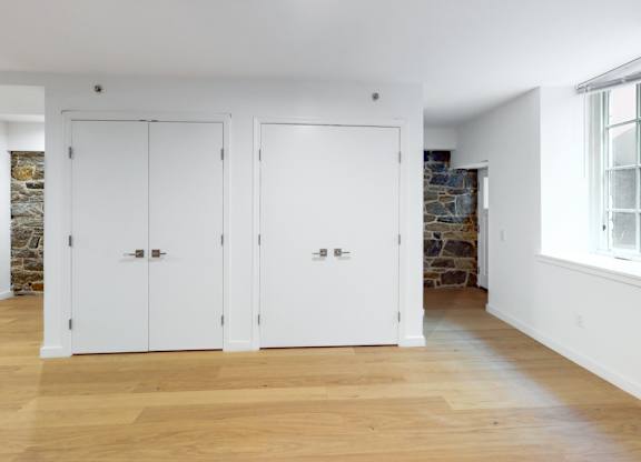 Three white doors are in a room with wood floors.