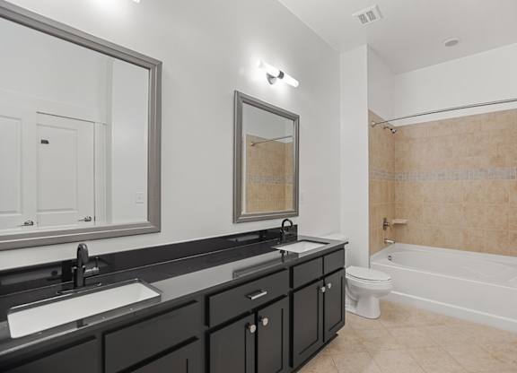 A bathroom with a white tub, sink, and mirror.