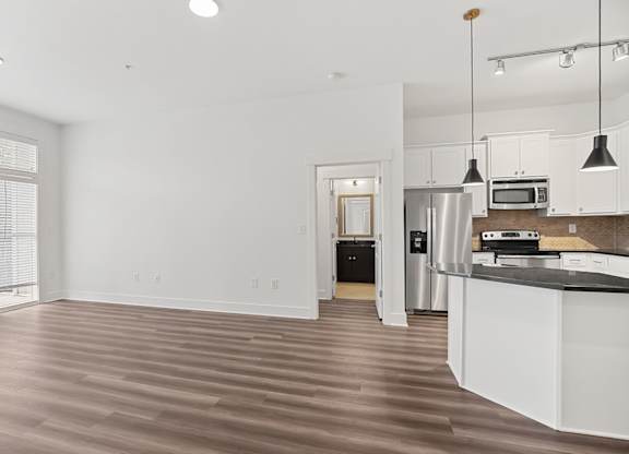 A kitchen with white cabinets and a wooden floor.