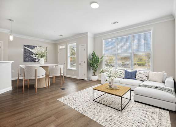 A living room with a white couch, a coffee table, and a dining table with chairs.
