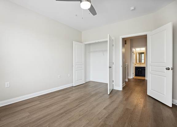 A room with a ceiling fan and light, and a doorway leading to another room.