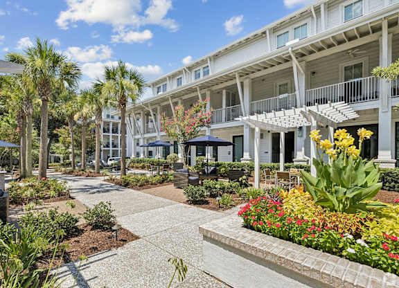 A sunny day at a resort with a walkway and buildings in the background.