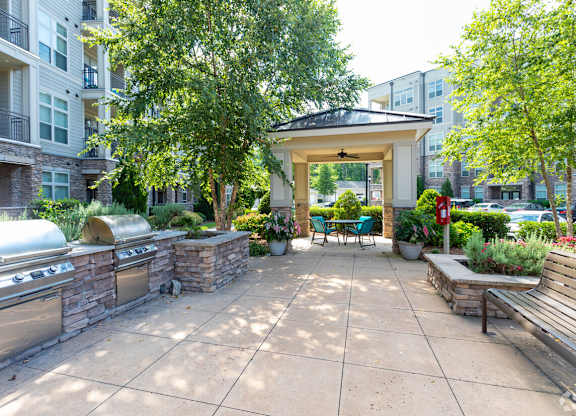 A patio with a gazebo, benches, and a fire pit.