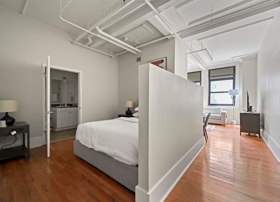 A bedroom with a bed, nightstand, and chair.