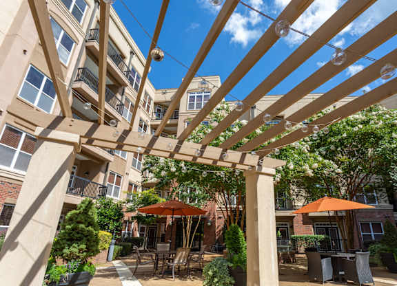 A patio with tables and chairs under a pergola.