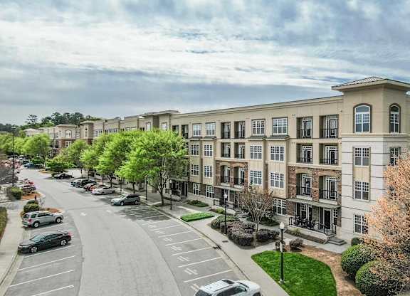 A street view of a row of apartment buildings with cars parked on the side of the road.
