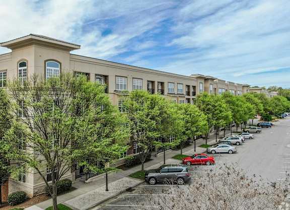 A row of townhouses with cars parked in front.