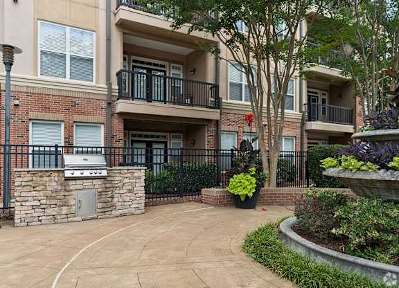 A brick building with a balcony and a small garden in front.