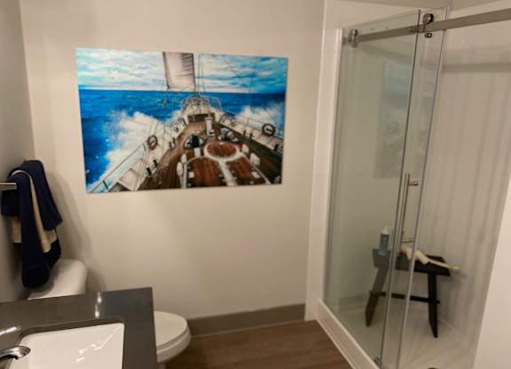 A bathroom with a large picture of a ship on the wall.