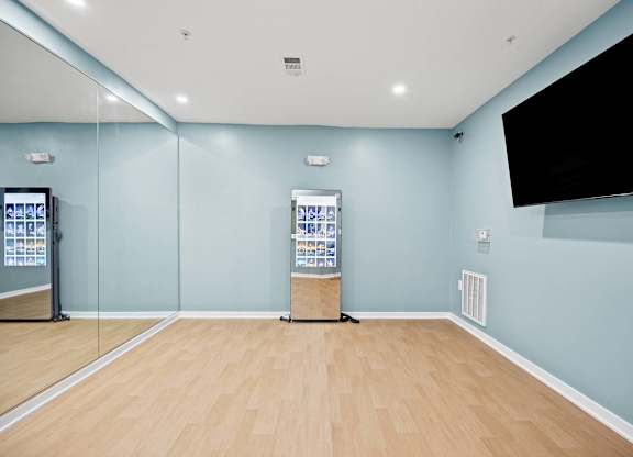 A room with a wooden floor and a wall-mounted television.
