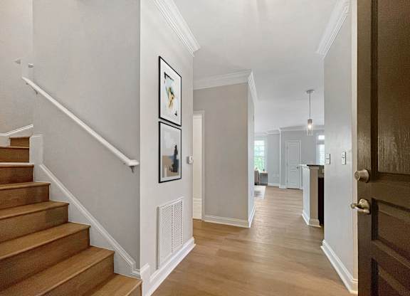 A hallway with a staircase and a doorway leading to another room.