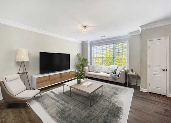 A modern living room with a white chair, a black television, and a glass coffee table.