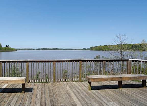 A wooden deck overlooks a body of water with benches on either side.
