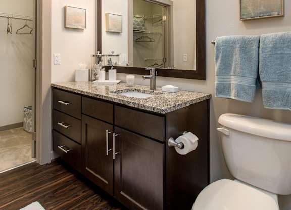 A bathroom with a toilet, sink, and mirror.