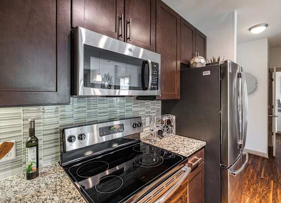 A modern kitchen with dark wood cabinets and stainless steel appliances.