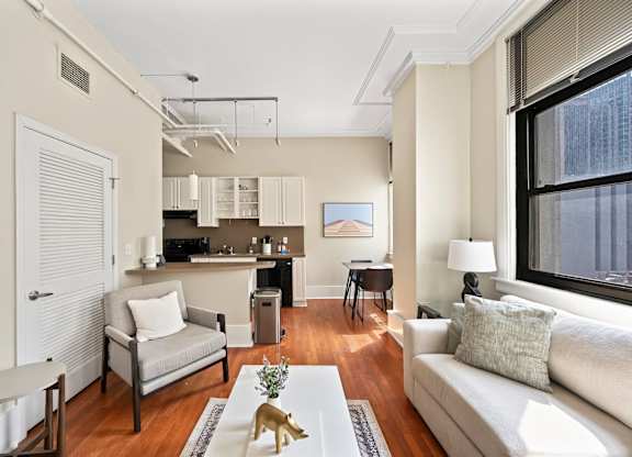 A living room with a grey couch and a coffee table with a gold vase on it.