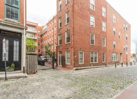A cobblestone street leads to a red brick building.