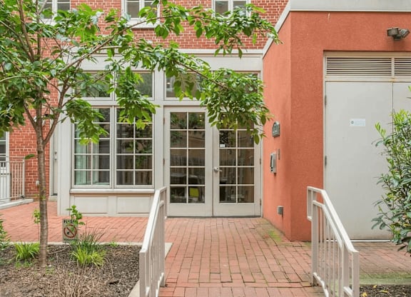 A red brick building with a white door and a tree in front.