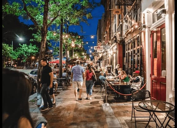 A group of people are walking down a street at night.