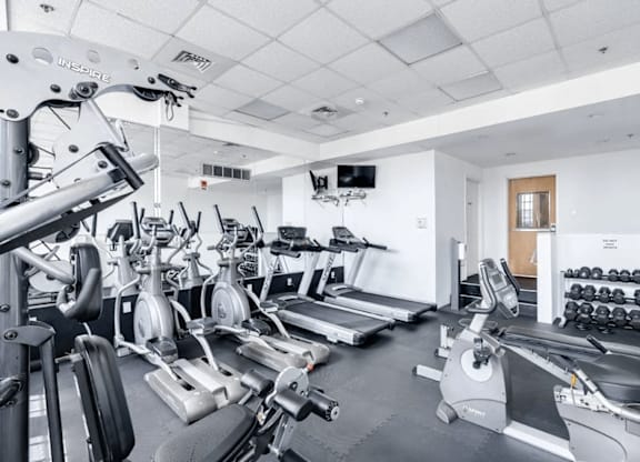A gym with a variety of equipment including treadmills, weights, and exercise machines.