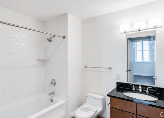 A white bathroom with a black counter top and a white toilet.