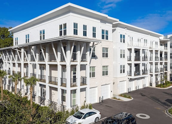 A white building with balconies and a car parked in front.