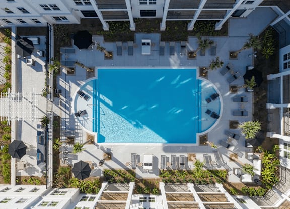 A swimming pool surrounded by lounge chairs and umbrellas.
