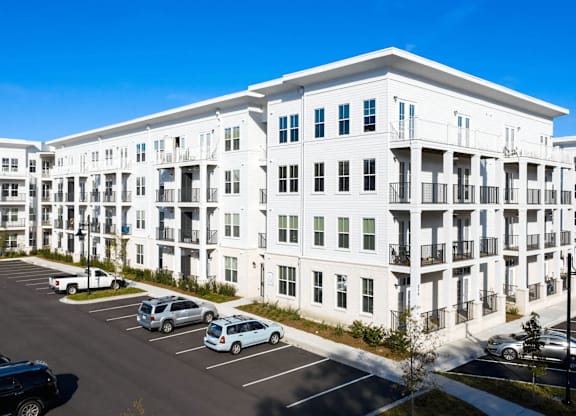 A white apartment building with cars parked in the parking lot.