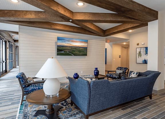 A living room with a blue couch and a painting on the wall.