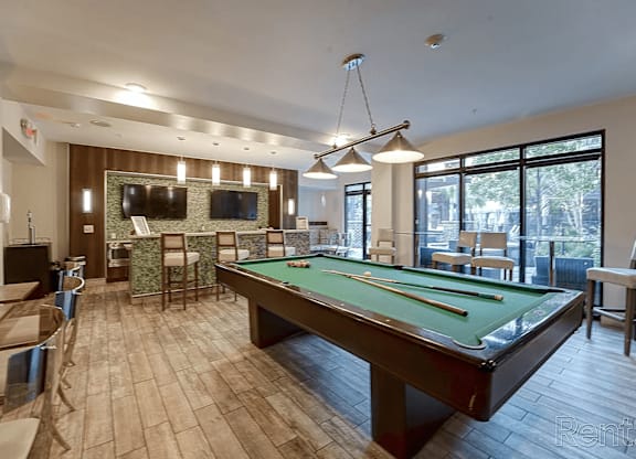 A billiards table is in the middle of a room with a pool table and a television.